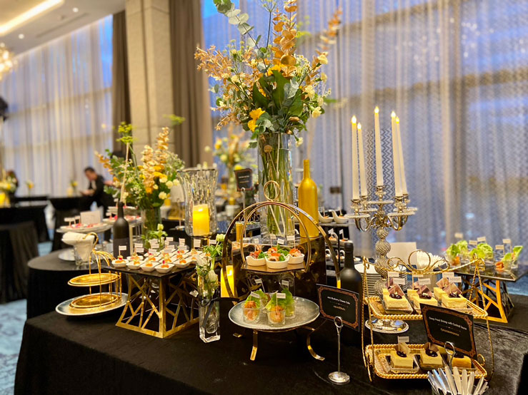 การจัดเลี้ยงนอกสถานที่สุดหรูหราโดย Set and Serve Catering พร้อมการตกแต่งโต๊ะค็อกเทลและดอกไม้สวยงามในงานเลี้ยงที่กรุงเทพฯ
